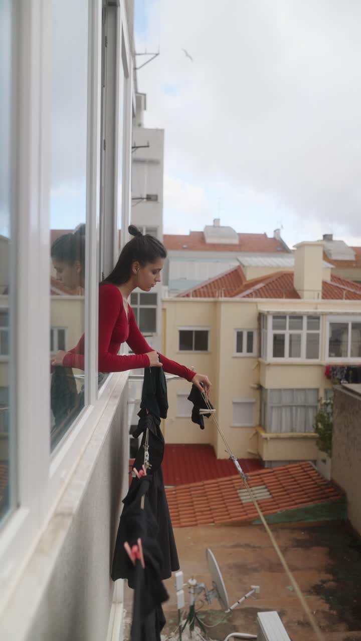 Woman Drying Clothes on a Balcony