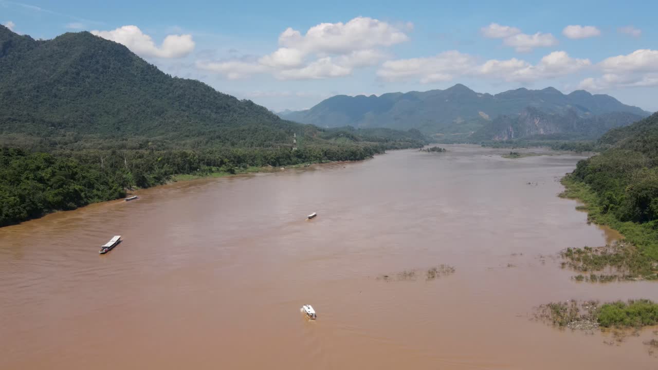 vuelo aéreo sobre el poderoso río mekong en un día soleado con barcos fluviales vistos cruzándolo en luang prabang