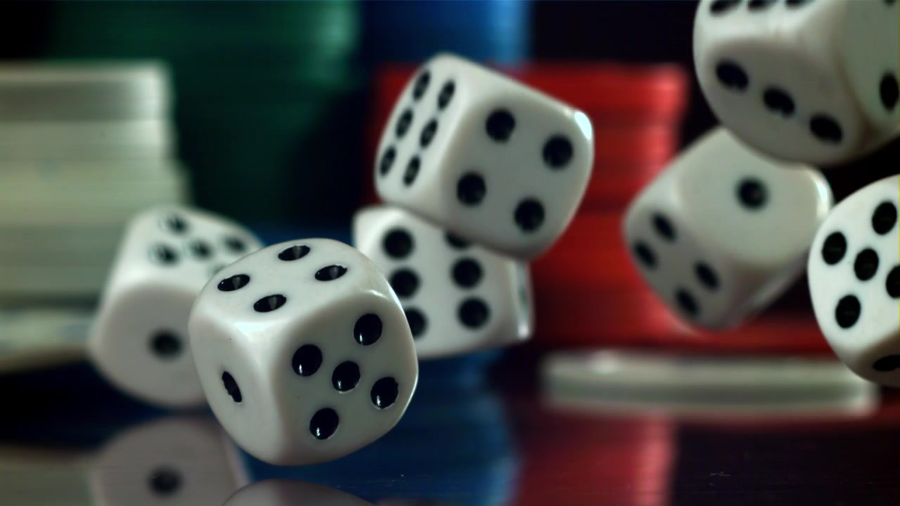 Movimento rallentato di dadi bianchi che cadono su una superficie riflettente con fiches da poker