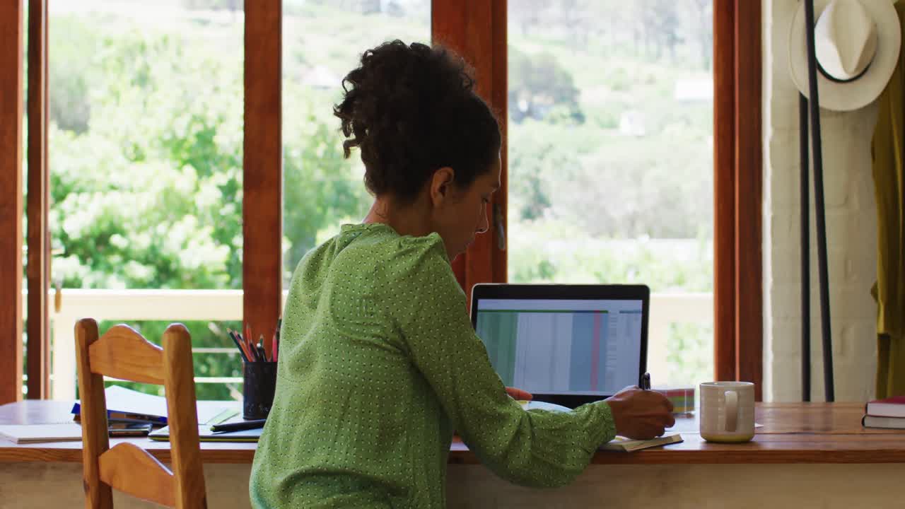 Mixed race woman taking notes while working from home