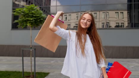 Pretty-girl-walking-from-centre-mall-with-shopping-bags,-happy-with-purchase-on-Black-Friday