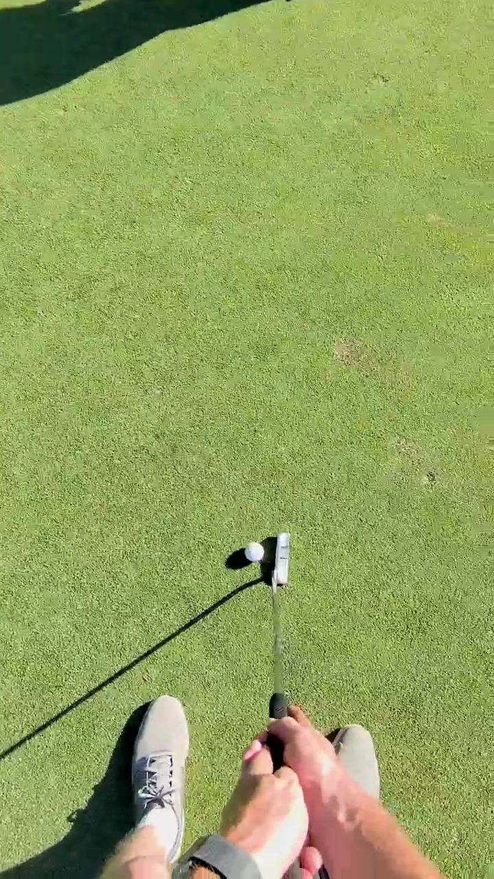 First-Person View of a Person Putting a Golf Ball on a Green