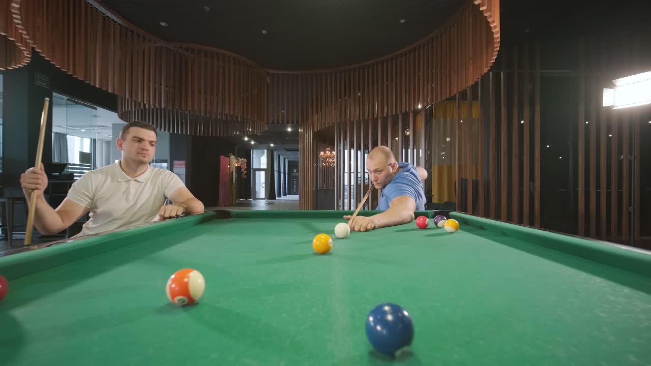 Adult men with disabilities in a wheelchair play billiards in the club