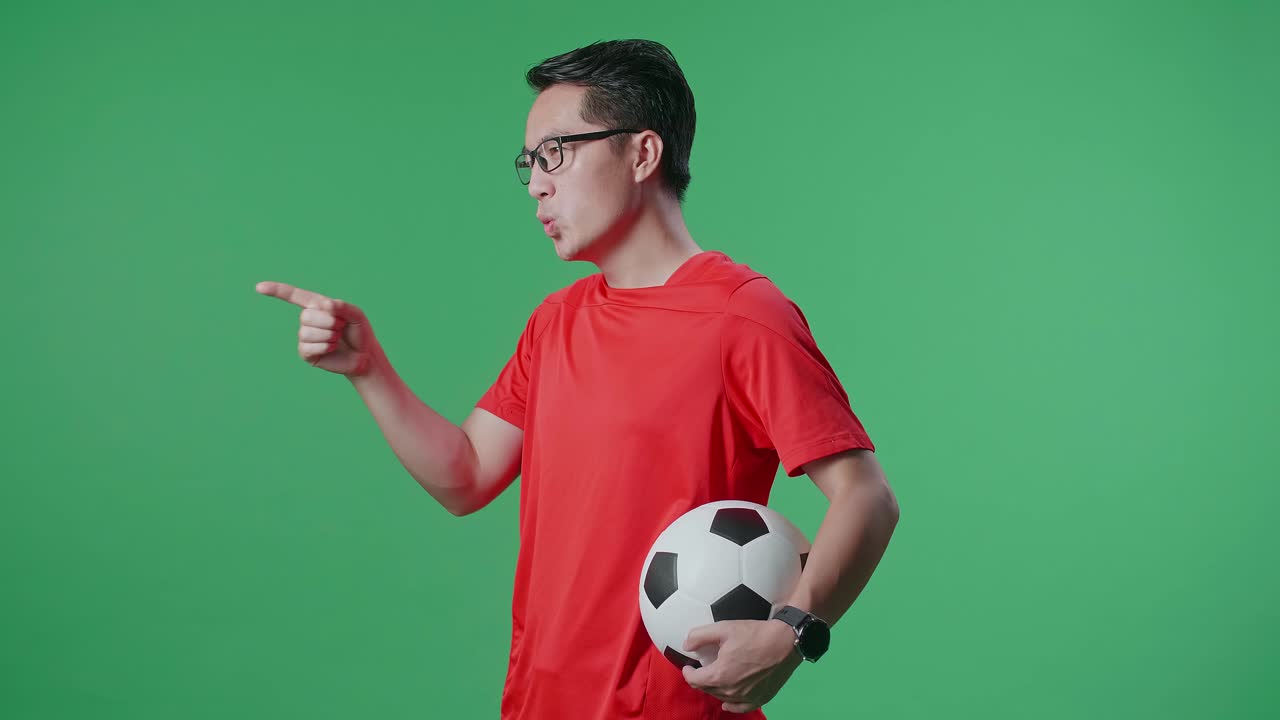hombre en camiseta roja de fútbol apuntando con una pelota de fútbol