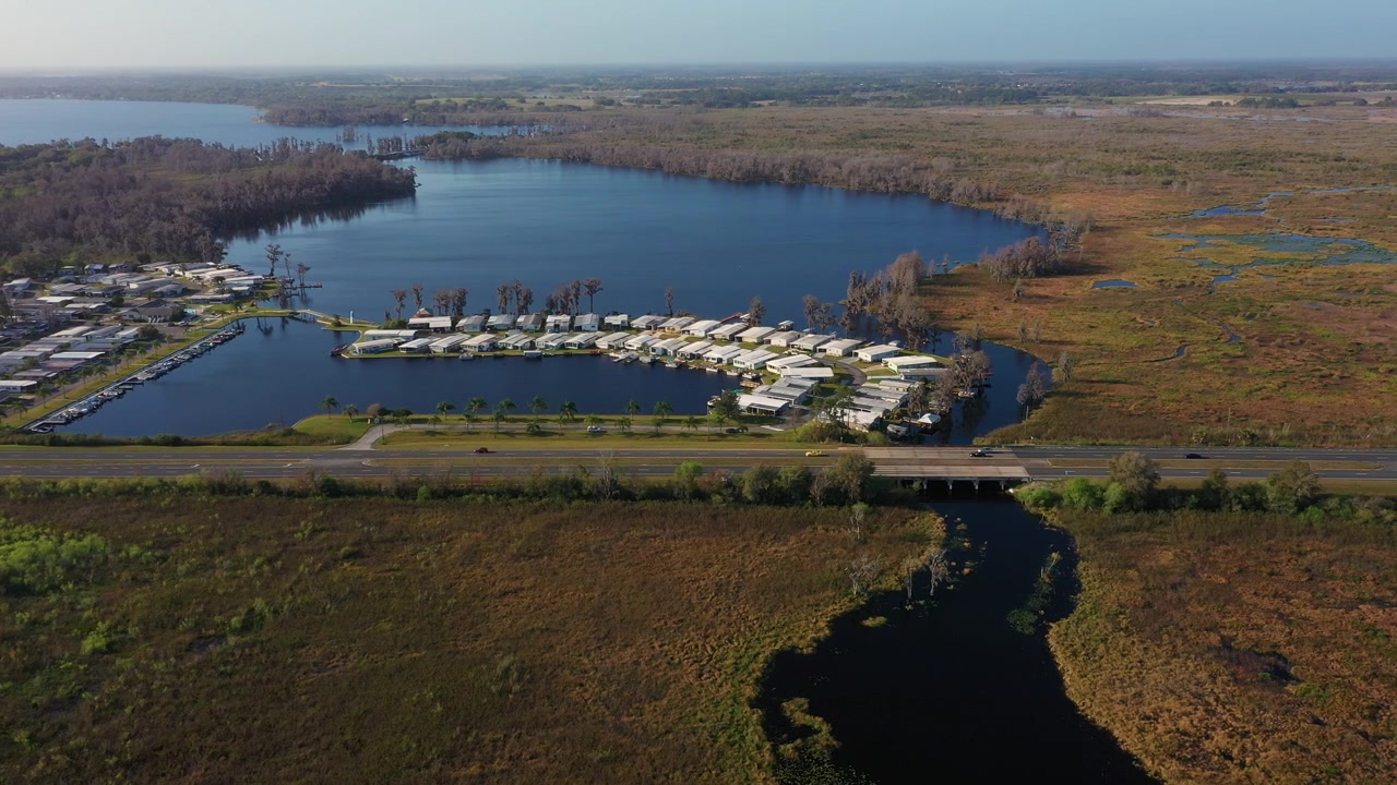 Ripresa con drone del fiume Palatlakaha che serpeggia attraverso le zone umide accanto a una comunità residenziale a Clermont, Florida, con il lago Minneola visibile in lontananza
