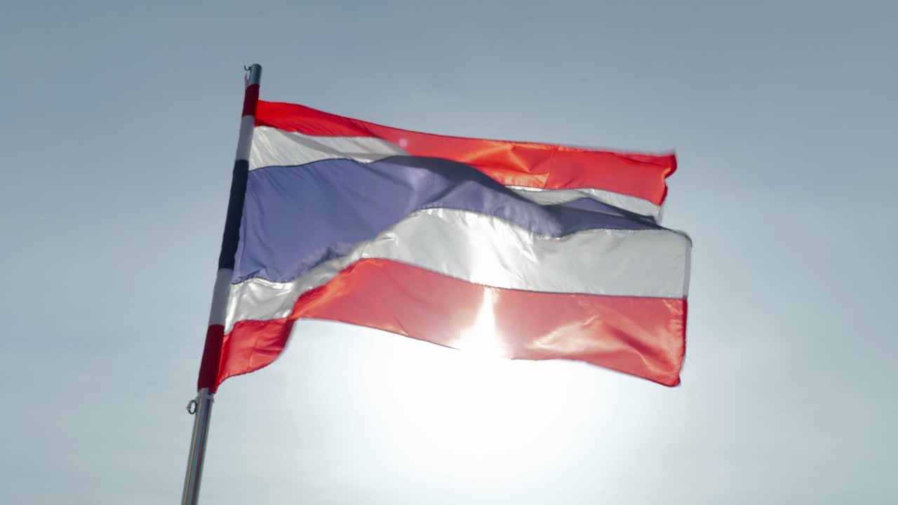 Close-up footage of the national flag of Thailand, known as the Tricolor or Thong Trairong, waving proudly in the wind. Symbol of Thai identity, patriotism, and national pride