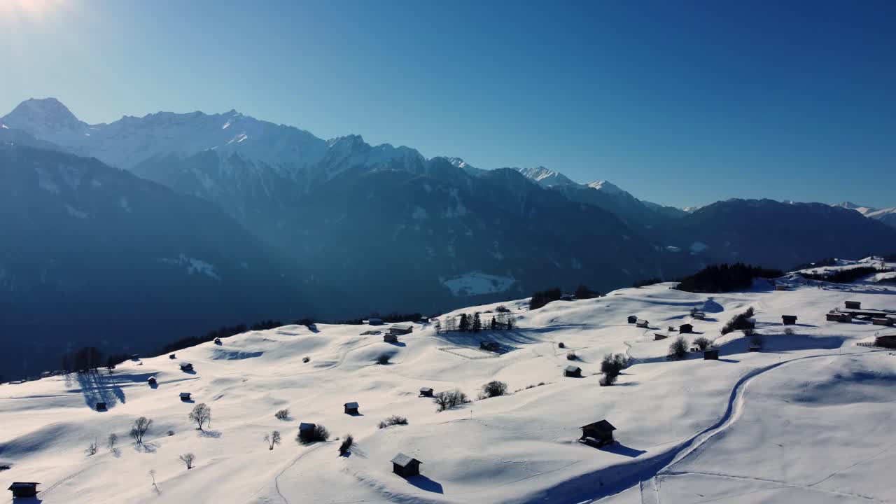 la brillante luz del sol de la tarde brilla en el campo ondulado con nieve en los alpes