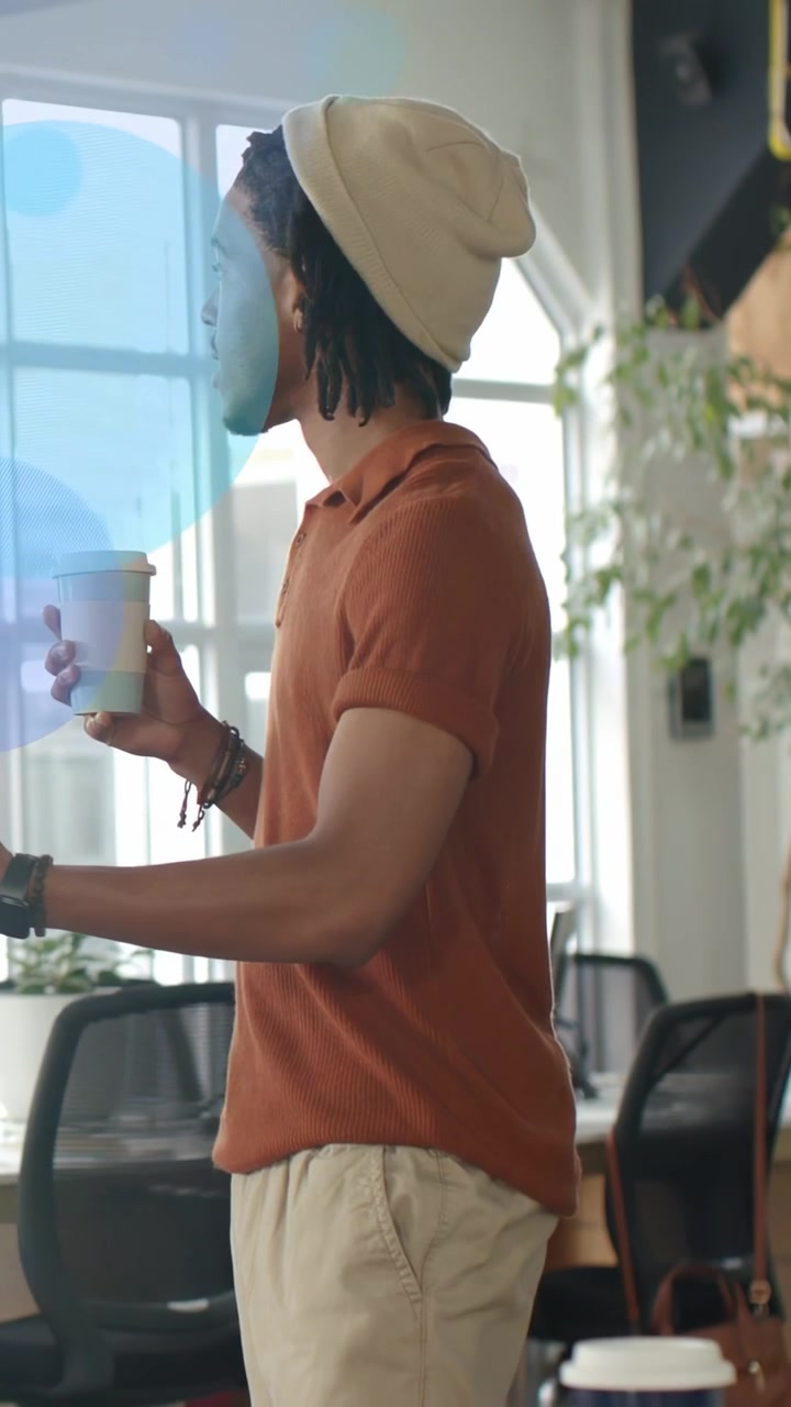 Vertical video: Office man on cue shifting, gesturing, holding cup, soft circles drifting over him