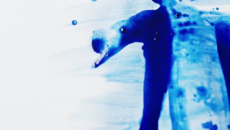 close up of blue paint shapes on white background with copy space, slow motion