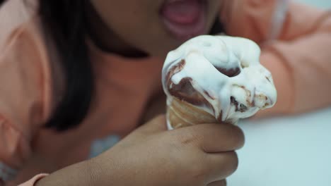 niño comiendo un cono de helado de chocolate y vainilla derretido