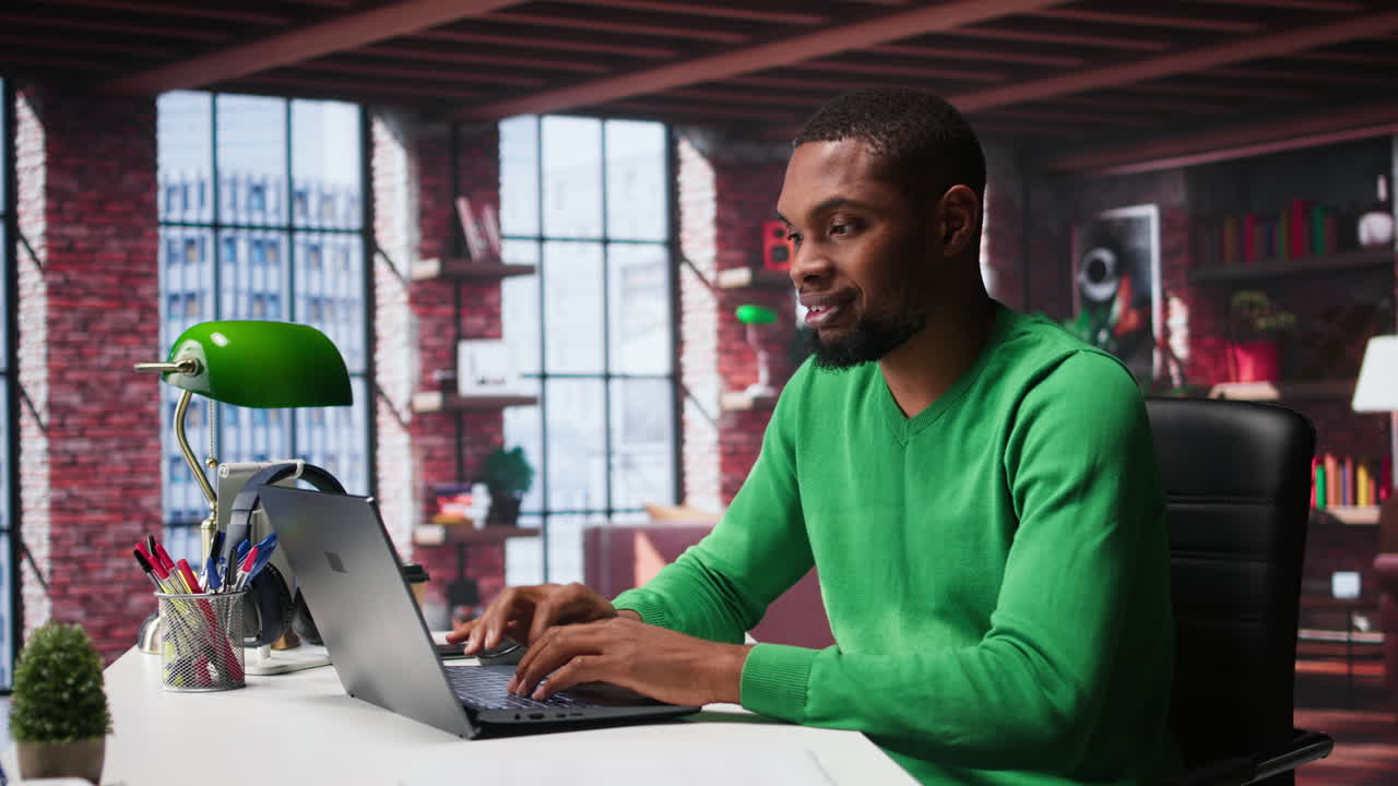 Video verticale. Lavoratore remoto afroamericano che risolve i suoi compiti quotidiani da freelancer sul laptop.