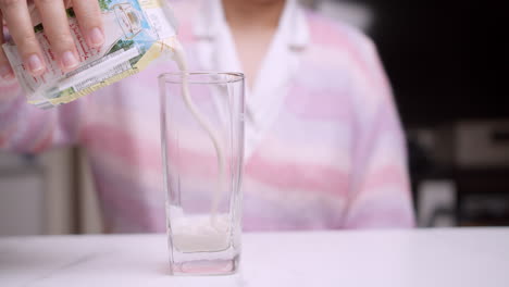 detail of woman pouring milk into glass cup