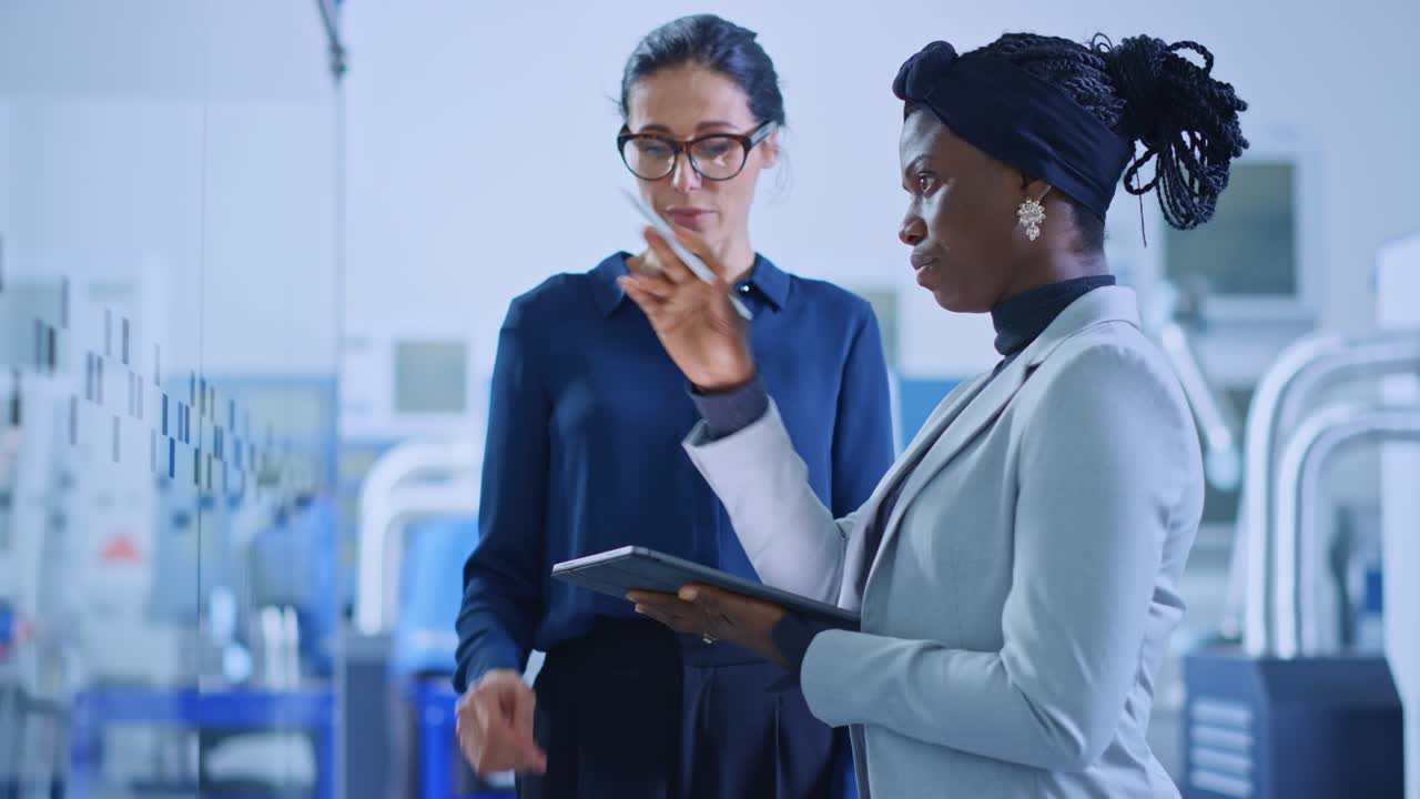 ingeniero industrial habla con el supervisor del proyecto, usan una tableta digital y discuten la planificación moderna de la fábrica. instalación de fabricación con maquinaria cnc y línea de ensamblaje de brazo robótico