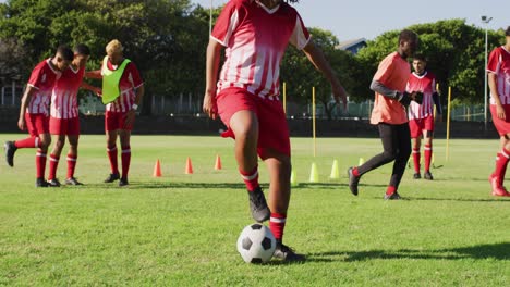 Video-Einer-Gemischten-Gruppe-Männlicher-Fußballspieler,-Die-Sich-Aufwärmen-Und-Den-Ball-Kicken