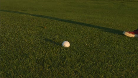 a golfer lining up a shot with a ball on a golf course