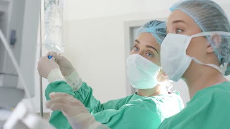 diverse surgeons wearing surgical gowns, applying drip in operating theatre, slow motion