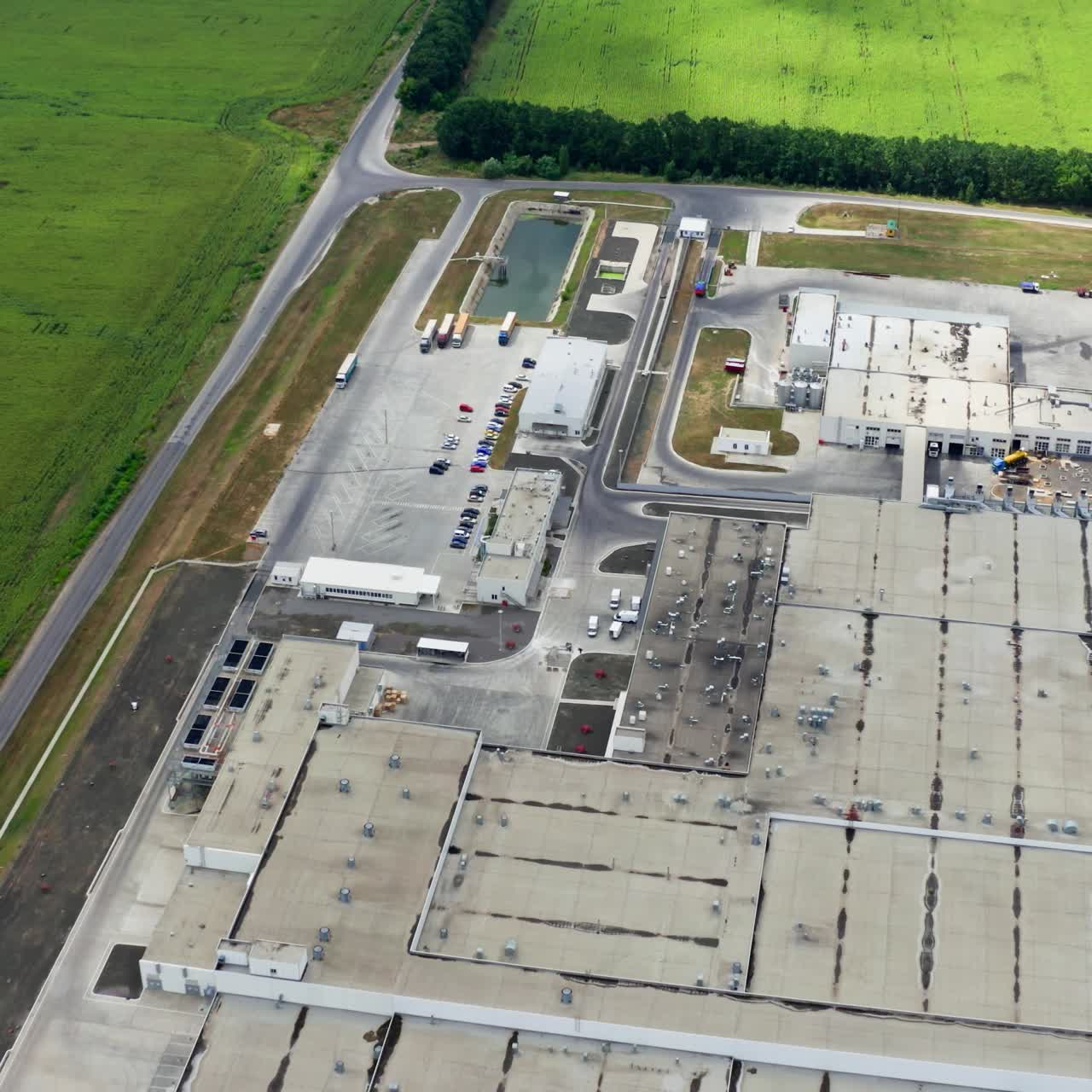 Industrial complex on field. Large territory of a plant with parking places on green fields. Manufacturing among nature. Aerial view