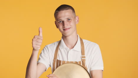 junger kellner in uniform, der den daumen hochgibt