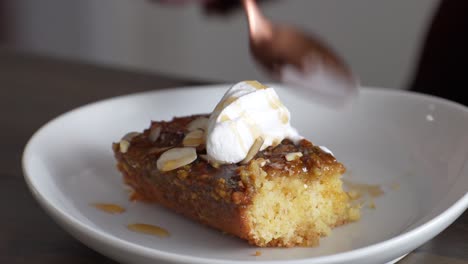 person eating a slice of banana caramel cake topped with white icing in a restaurant