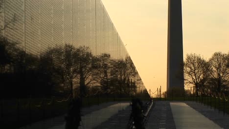 Con-Un-Cielo-Dorado-Como-Telón-De-Fondo,-El-Monumento-De-Washington-Se-Ve-En-Silueta-Junto-Al-Muro-Conmemorativo-De-Vietnam.