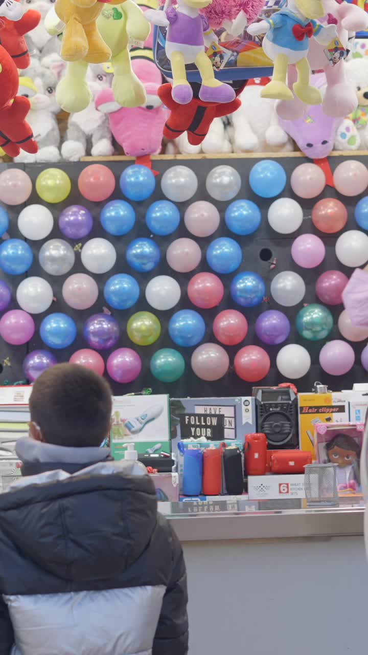 Child playing a balloon dart game at a carnival