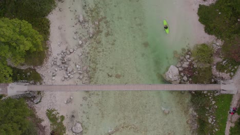 Green-kayak-next-to-old-wooden-bridge-in-Soca-valley,-Slovenia,-aerial