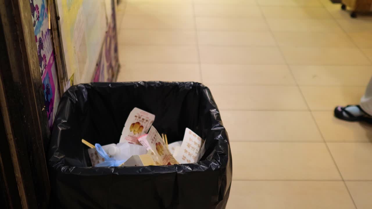 사람이 쓰레기통에 음식 용기를 버립니다.