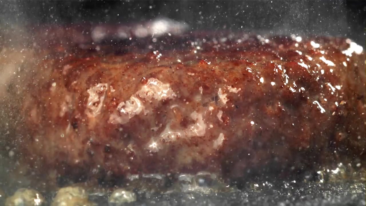 Pølse steger på varm pande med sydende olie i slowmotion