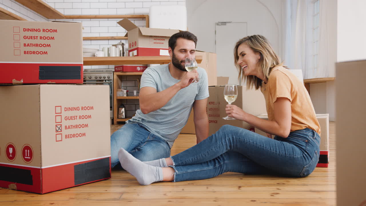 pareja celebrando mudarse a una nueva casa haciendo un brindis con vino