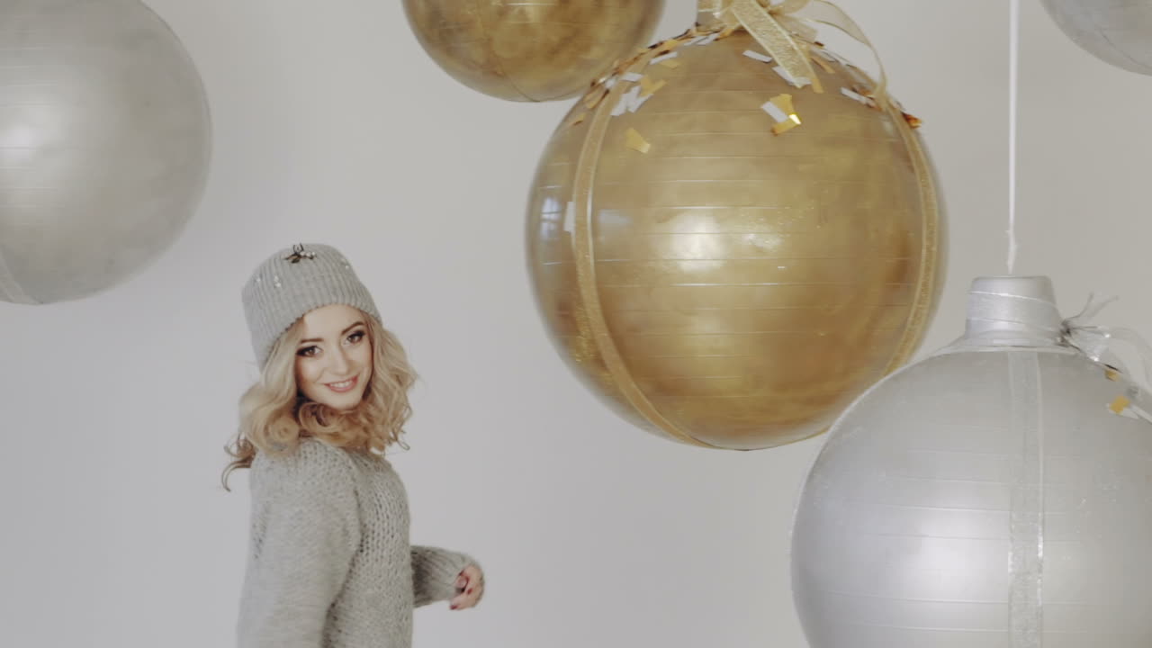 Christmas holiday party. Smiling girl throwing confetti balloons on background