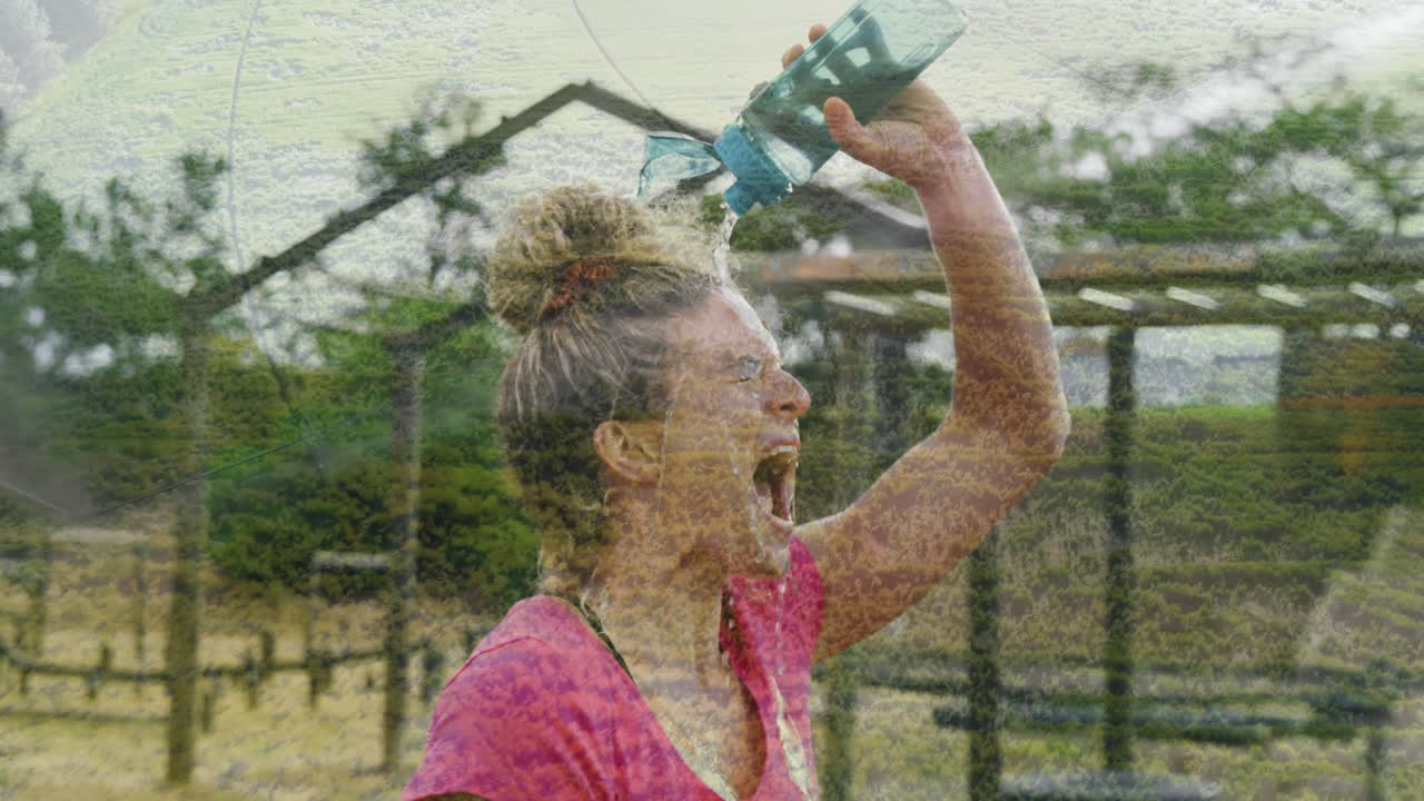 Pouring water over herself outdoors, woman in pink shirt looking refreshed