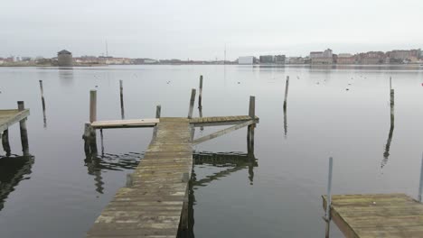 closing in on a group of birds in the water over three older wooden bridges in the beautiful swedish naval city of karlskrona with a background of the fortress godnatt out in the still water