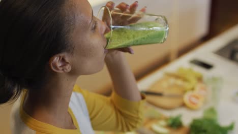 Mujer-De-Raza-Mixta-Bebiendo-Bebidas-Saludables-En-La-Cocina