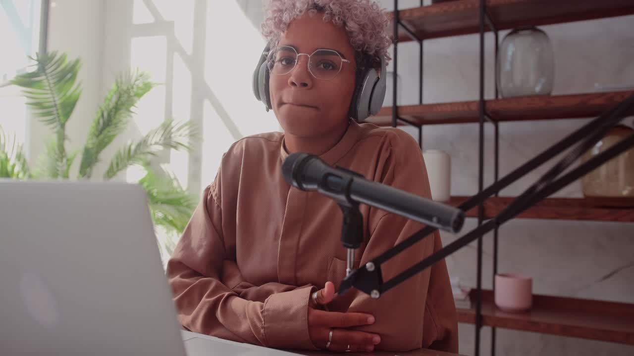 Young african woman blogger recording online podcast using streaming microphone