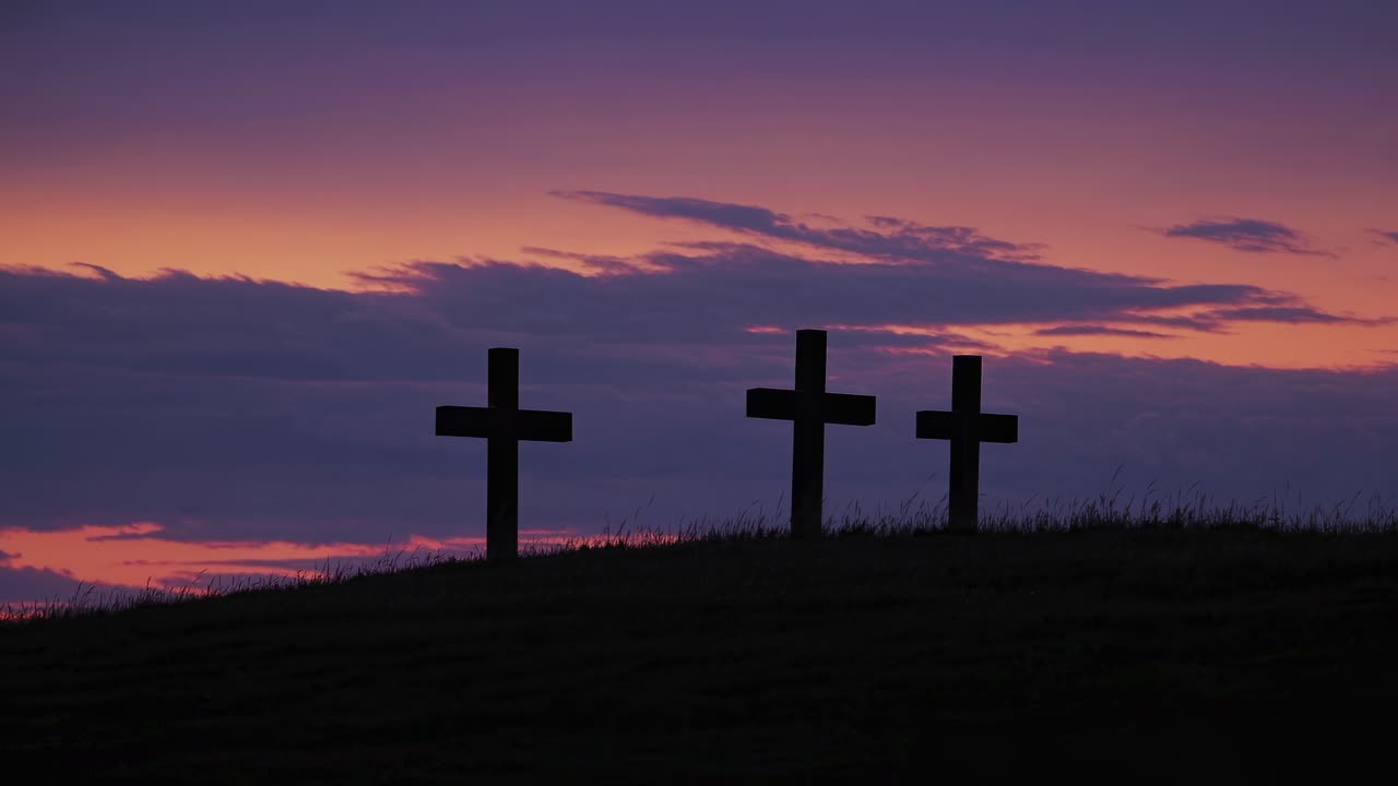 Silhouetted crosses on a hill at sunset, captured from a low angle