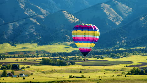 hot air balloon landing in mountains at sunrise - close aerial view