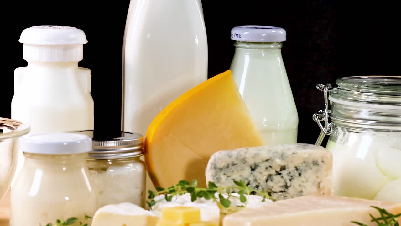 A variety of dairy items including cheese, milk, and yogurt displayed against a dark backdrop.