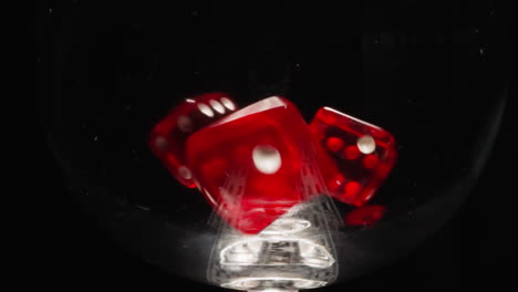 Small-red-cubes-with-dots-thrown-into-transparent-glass-dance