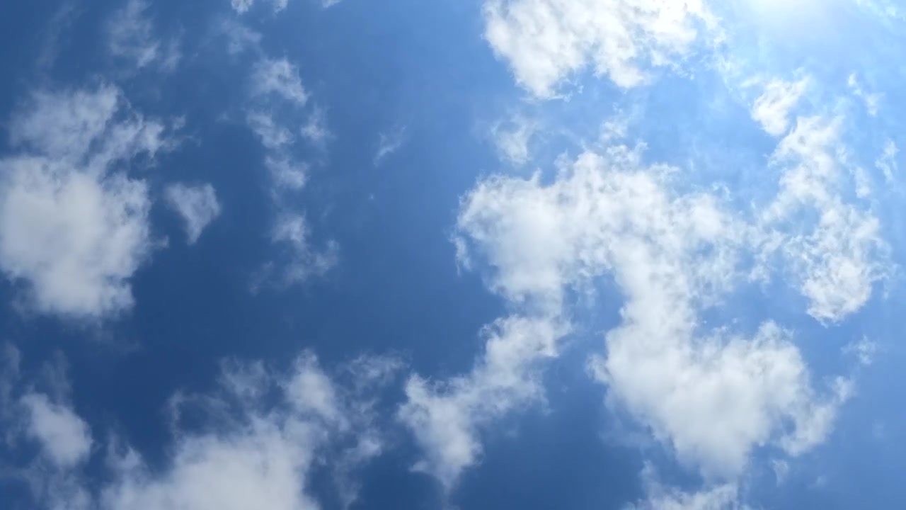 White fluffy clouds forming a heart shape in a vibrant blue sky with a faint vapor trail visible