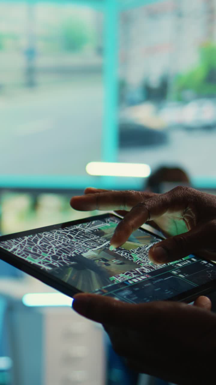 Primo piano di mani che usano un tablet con mappa e clip video di sorveglianza