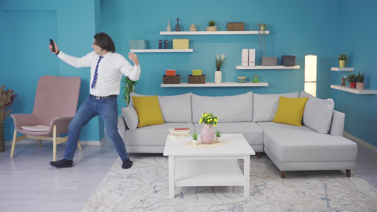 hombre de baile alegre y divertido mirando el teléfono en casa.