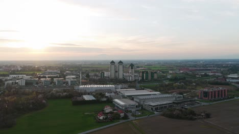 aerial view of vimercate skyline at sunset with modern buildings, green fields and industrial area in lombardy, italy