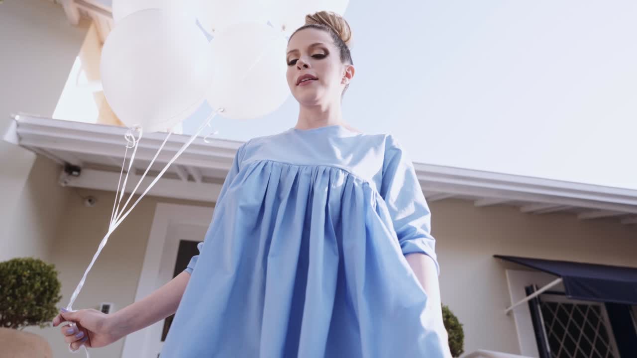 행복한 아름다운 라틴 여성이 도시를 고 있습니다. 젊은 금발 소녀는 느린 동작으로 하루를 즐기고 있습니다. 풍선과 함께 도시에서 습니다.