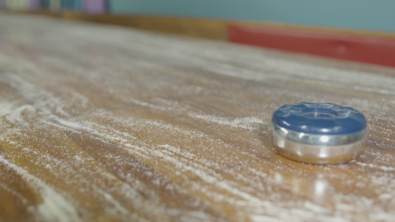 A static shot of two pucks sliding into view durning a shuffleboard game