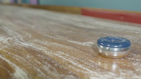 A-static-shot-of-two-pucks-sliding-into-view-durning-a-shuffleboard-game