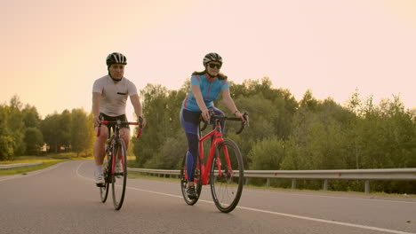 Ein-Mann-Und-Eine-Frau-Fahren-Bei-Sonnenuntergang-In-Montur-Und-Schutzhelmen-In-Zeitlupe-(120 fps)-Auf-Sporträdern-Auf-Der-Autobahn.