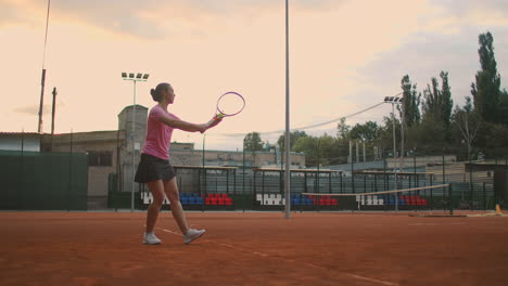 Para-El-Entrenamiento-De-Tenis,-Una-Niña-Se-Encuentra-En-La-Línea-De-Servicio-Central.-Golpea-La-Pelota-En-La-Cancha.-Atender.-Tiro-Largo