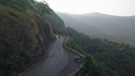 motorcycle rides down scenic mountain side road on hazy day in india