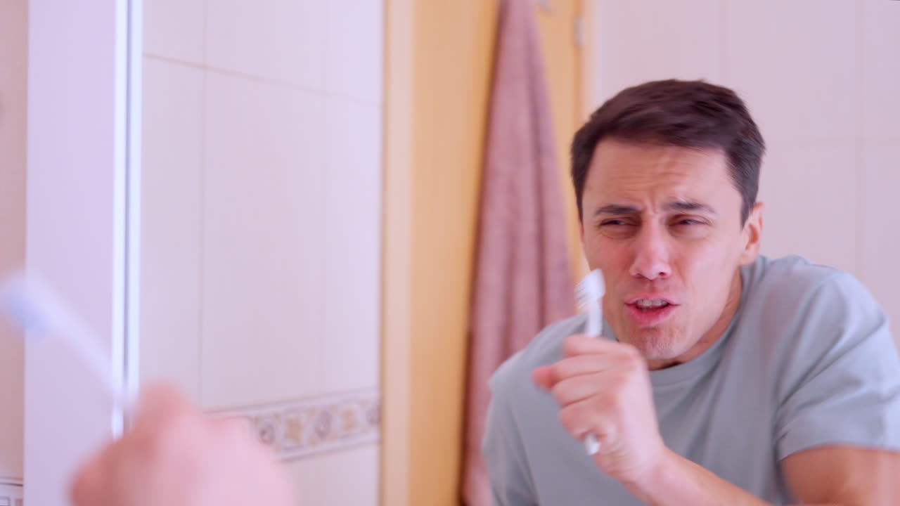 Enthusiastic man singing with toothbrush in bathroom mirror
