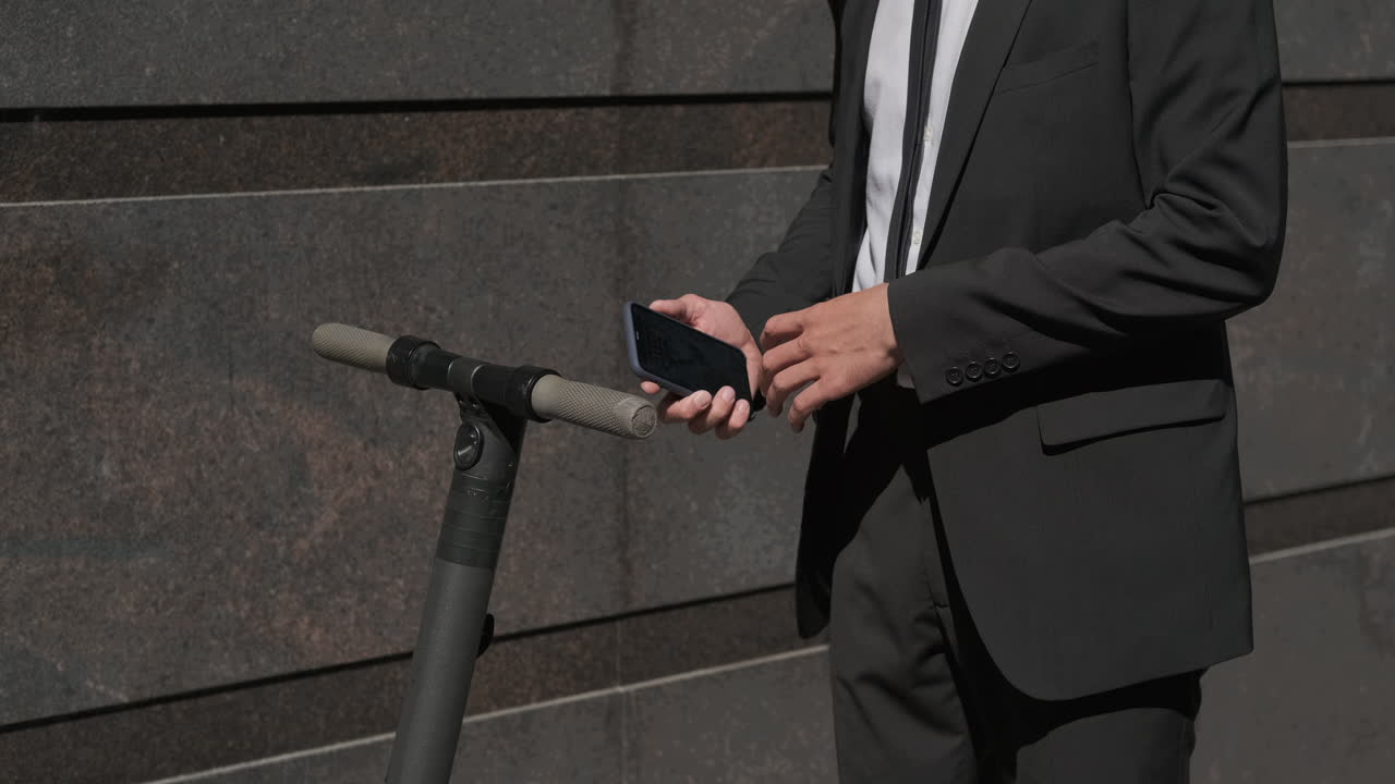 전기 스쿠터 근처에 전화를 사용하는 사업가